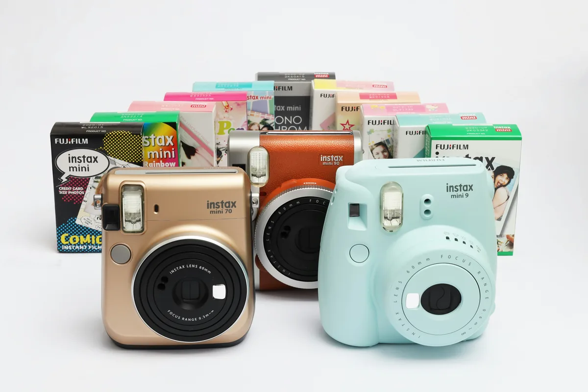 Tres cámaras Instax delante de una fila de cajas de película Instax mini de distintas ediciones