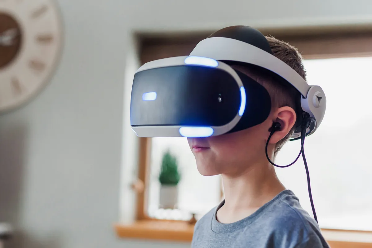 Un niño con un visor de realidad virtual blanco y auriculares, en una habitación con luz natural